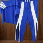 Coat Set Deportivo-Chic: Playera de Cuello Asimétrico con Rayas y Pants de Pierna Ancha con Slits Frontales.